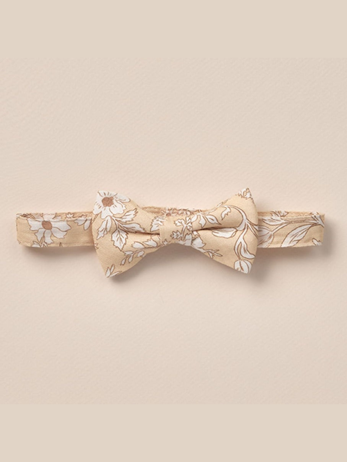 Floral beige bow tie on a soft background, ideal for formal attire or special occasions.