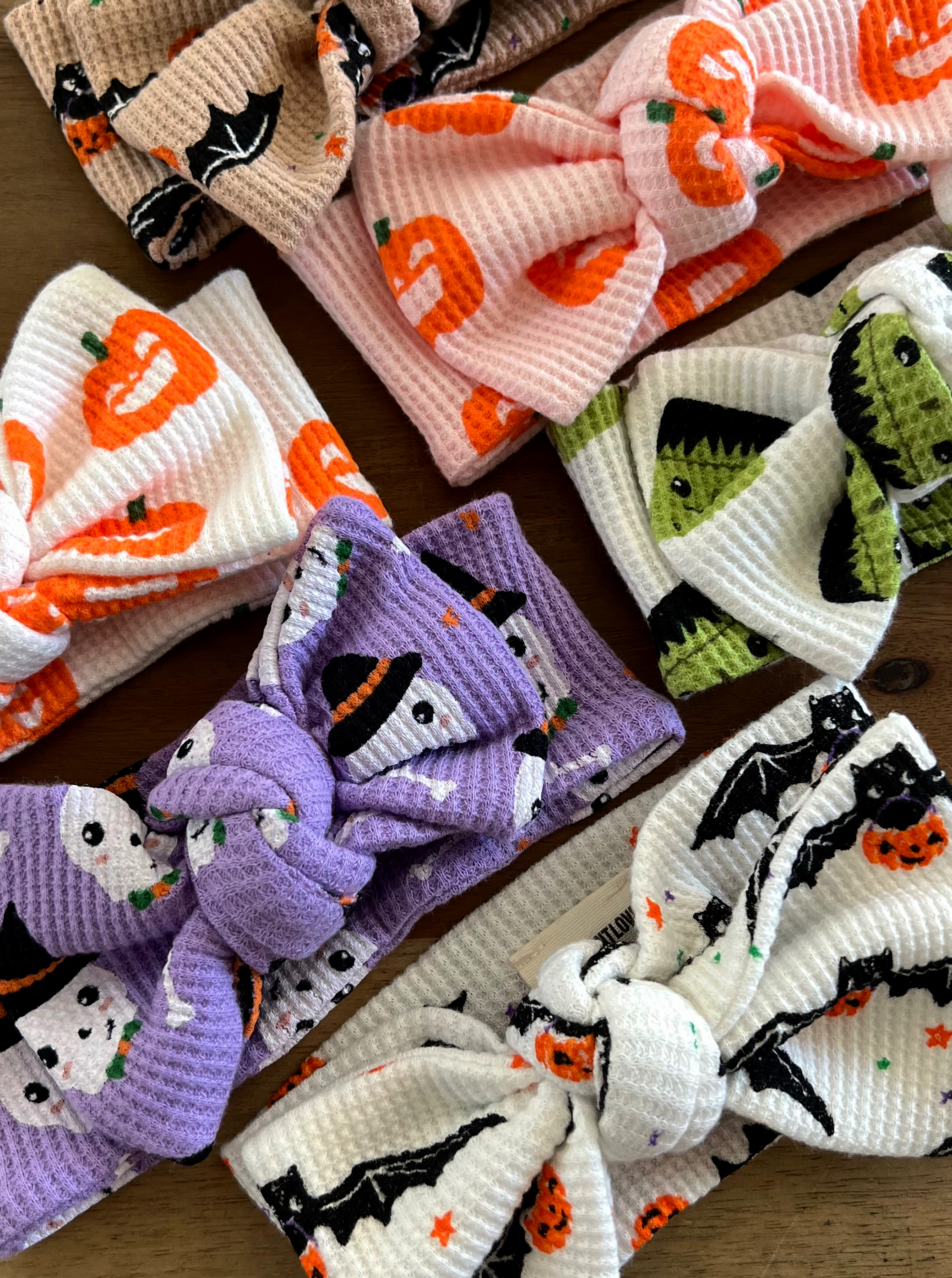 Assorted Halloween-themed headbands featuring pumpkins, ghosts, bats, and Frankenstein designs in various colors.