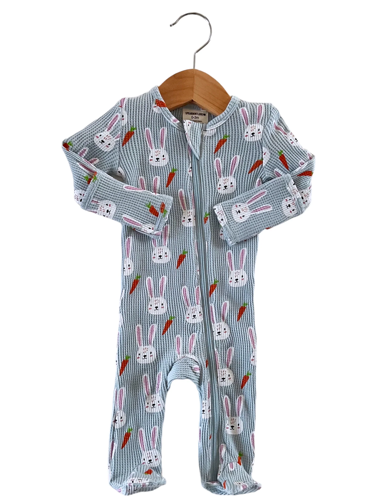 Light blue baby onesie with bunny and carrot pattern, hanging on a wooden hanger.