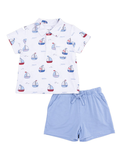 White children’s shirt with boat print, paired with light blue shorts. Ideal for summer wear.