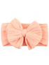 Peach textured headband featuring a large, decorative bow at the front. Ideal for accessorizing.
