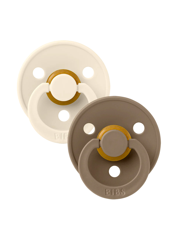 Set of two baby pacifiers in beige and brown, featuring a round shape and a safety handle.