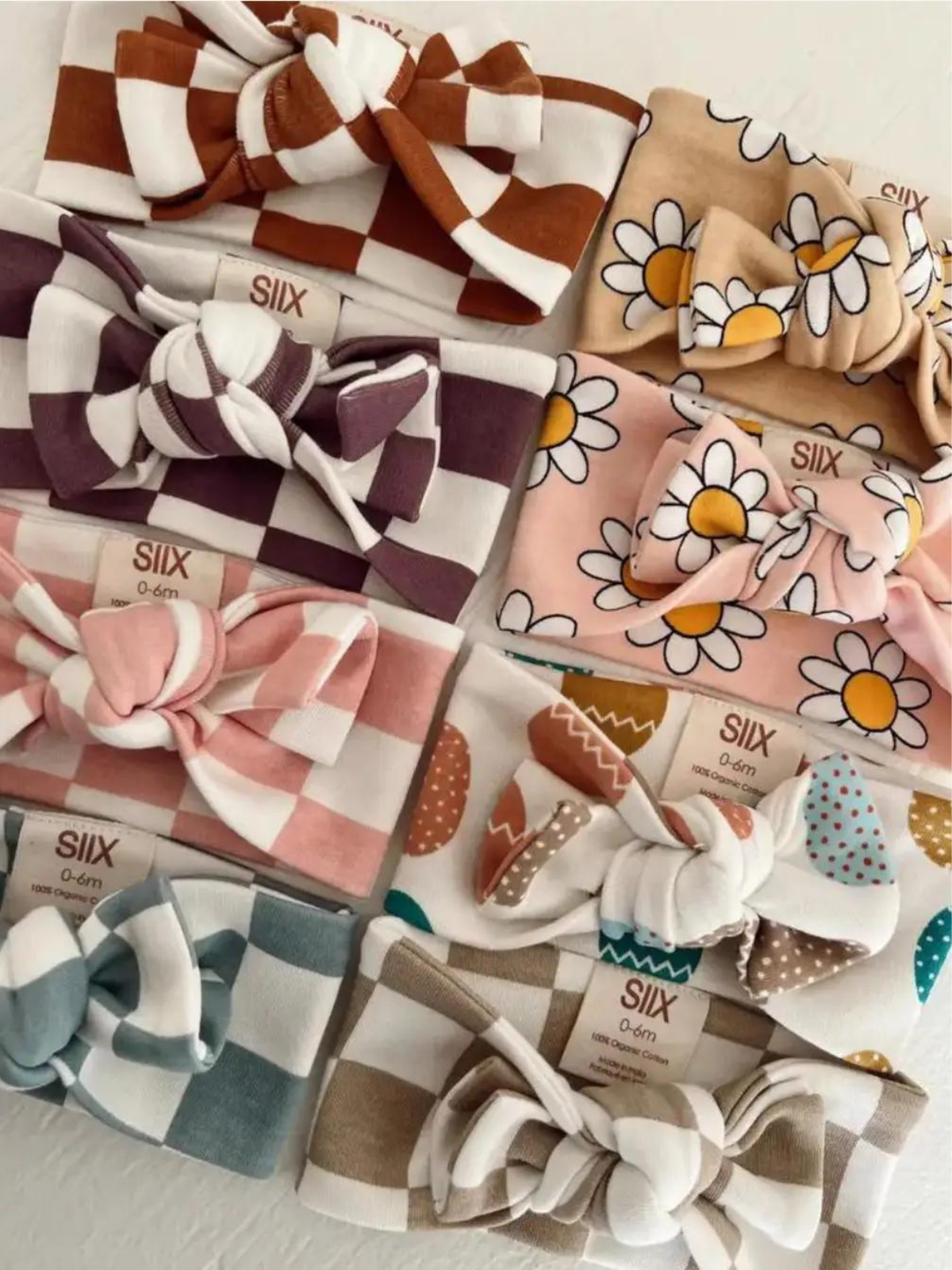 Colorful baby headbands with bows in various patterns, including florals and checks, displayed in a flat layout.
