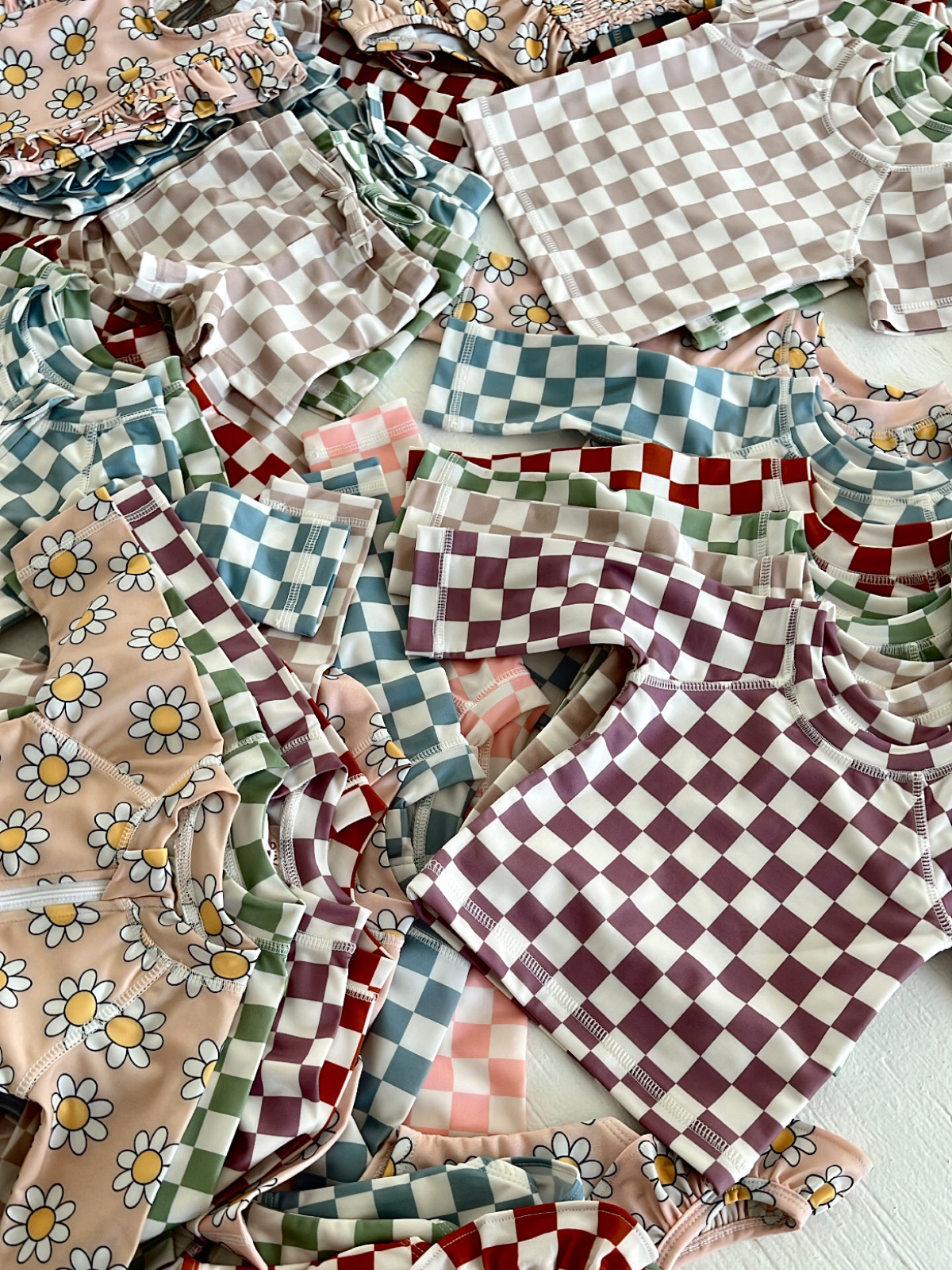 Colorful patterned children's clothing, featuring floral and checkered designs, arranged in a neat pile.