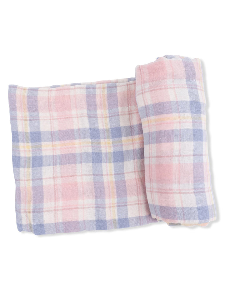 Soft plaid blanket in pastel pink, blue, and yellow hues, neatly rolled up and resting flat.