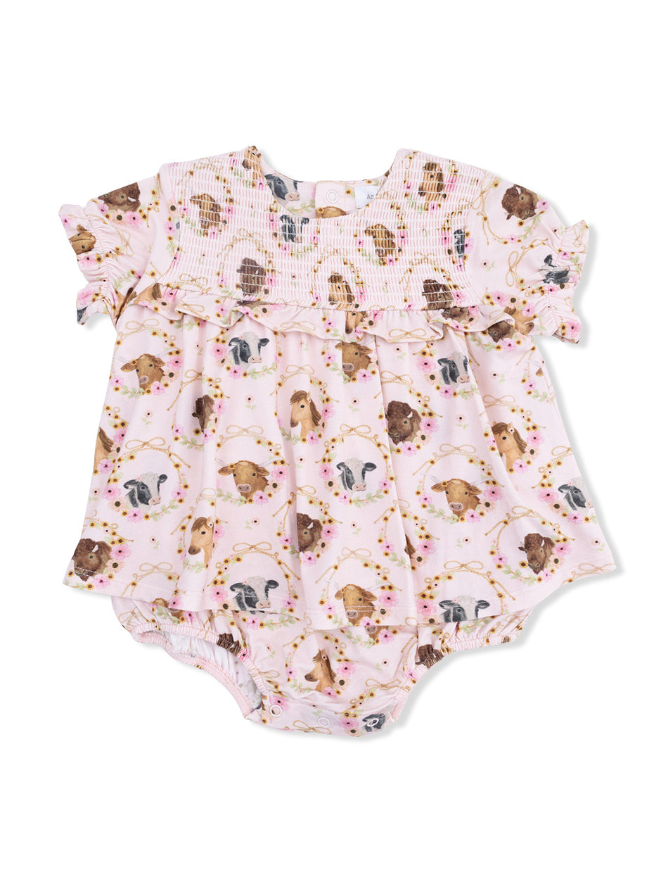 Light pink baby romper featuring various dog illustrations and floral accents with ruffled sleeves.