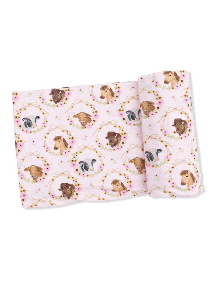 Pink fabric featuring illustrated animal heads in floral wreaths, including cows, horses, and dogs.