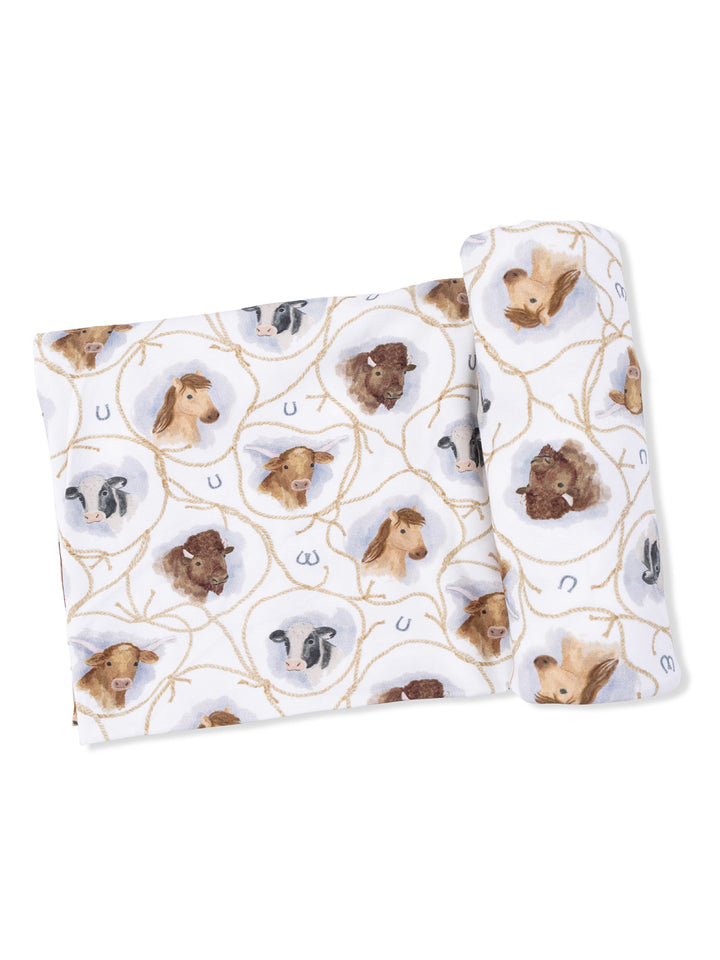 Fabric featuring animal heads, including horses and cows, with rope and horseshoe patterns on a white background.