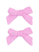 Two pink fabric hair bows with a textured finish, placed above each other.