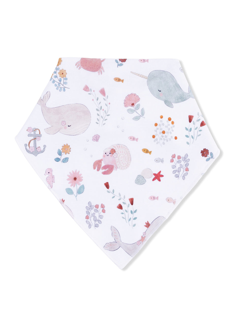 Whimsical baby bandana bib with illustrations of whales, narwhals, and sea creatures on a white background.