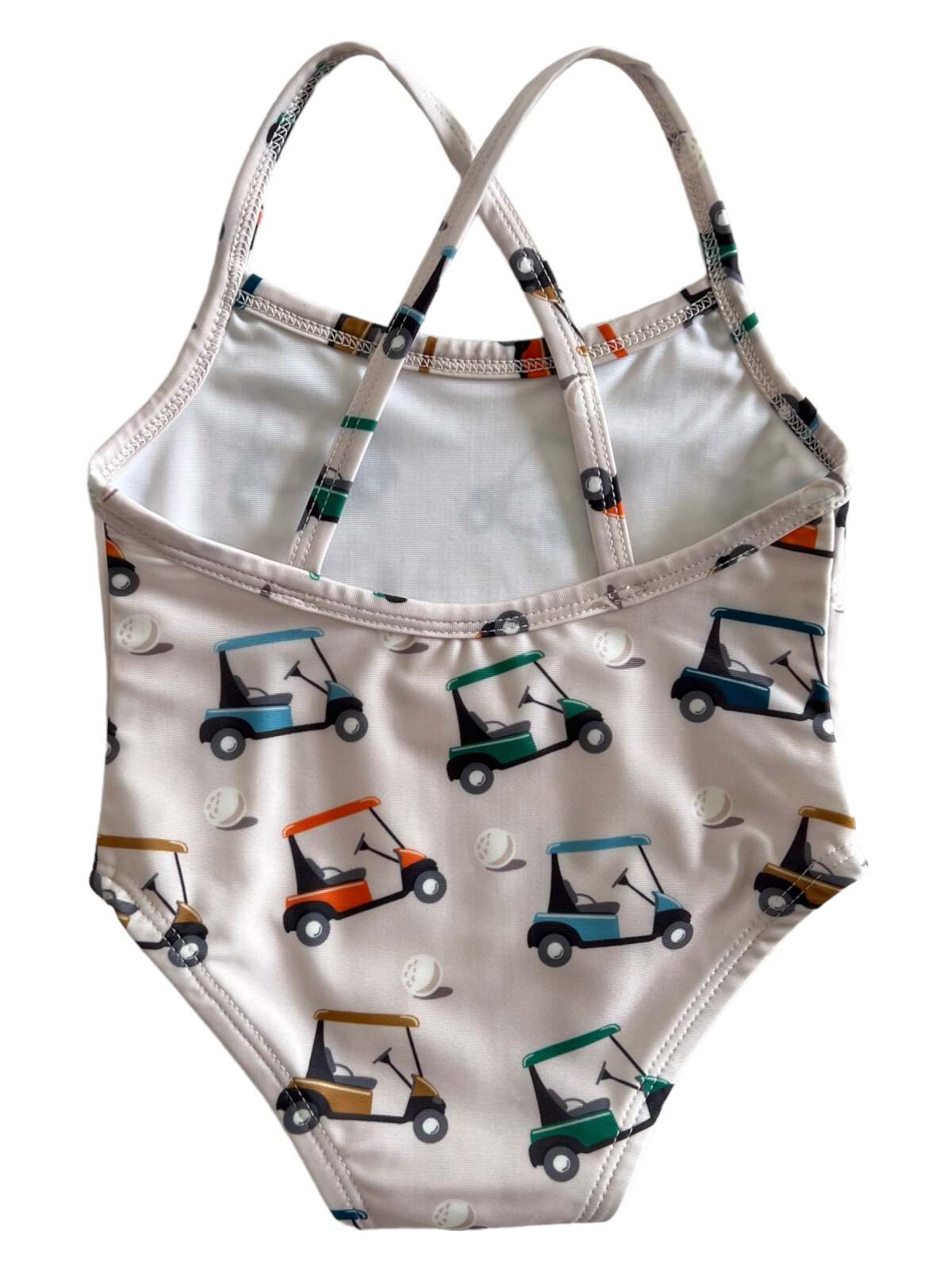Girls' swimsuit with golf cart pattern, featuring adjustable straps and light colors.