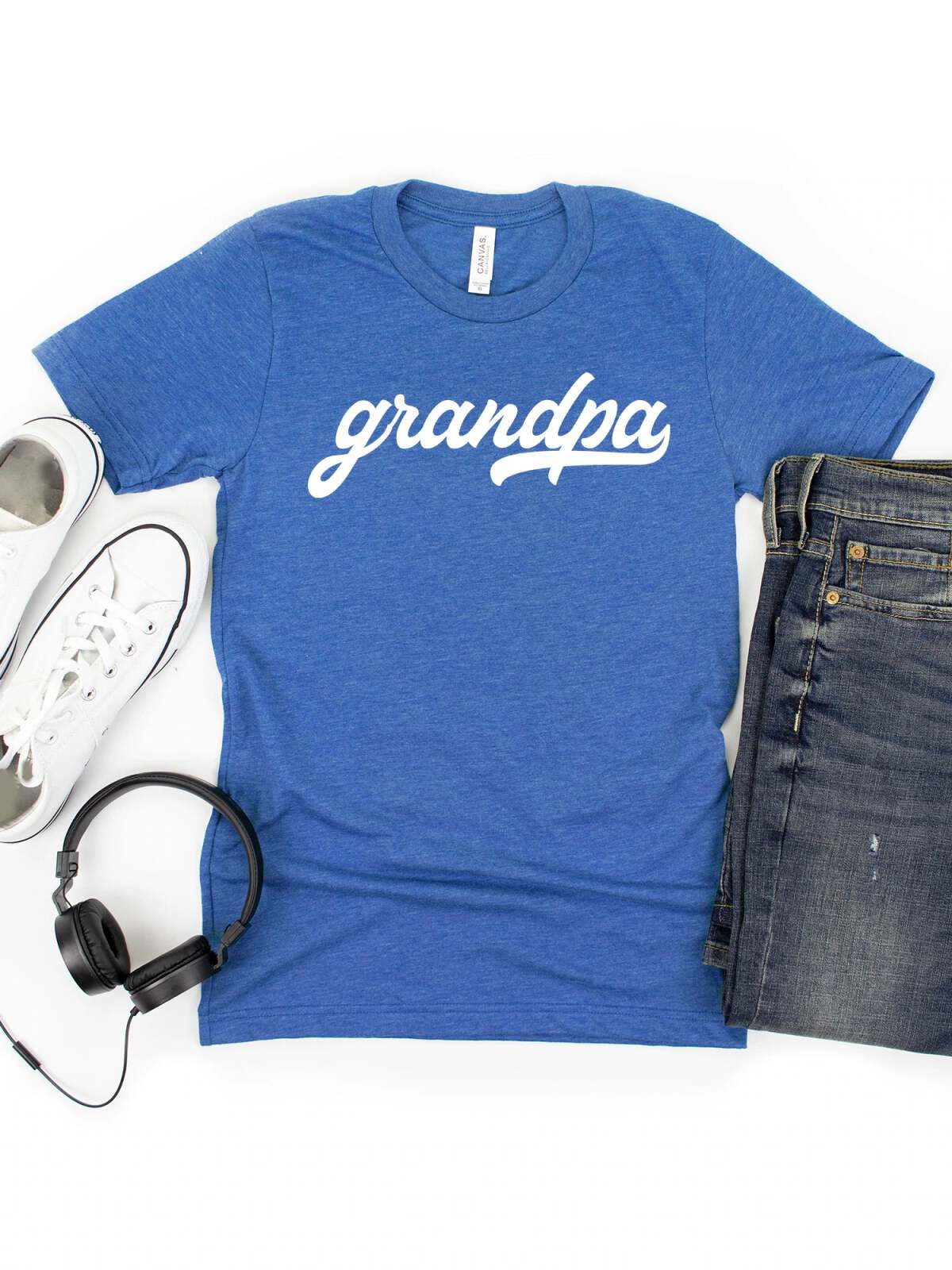 Blue t-shirt with "grandpa" in white script, paired with jeans, white sneakers, and headphones.