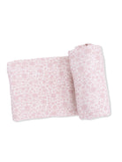 Light pink floral blanket, folded with one rolled end, on a white background. Ideal for cozy or decorative use.