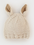 Knit beige beanie with bunny ears, softly textured, set against a white background.