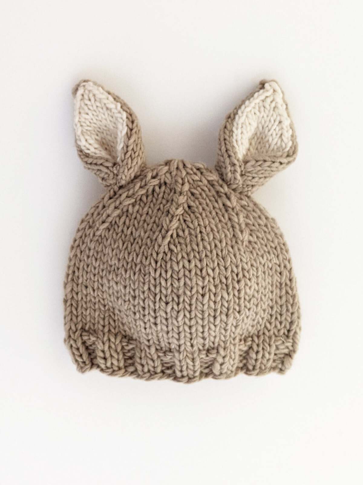Knitted beige hat with animal ears, displayed on a white background.