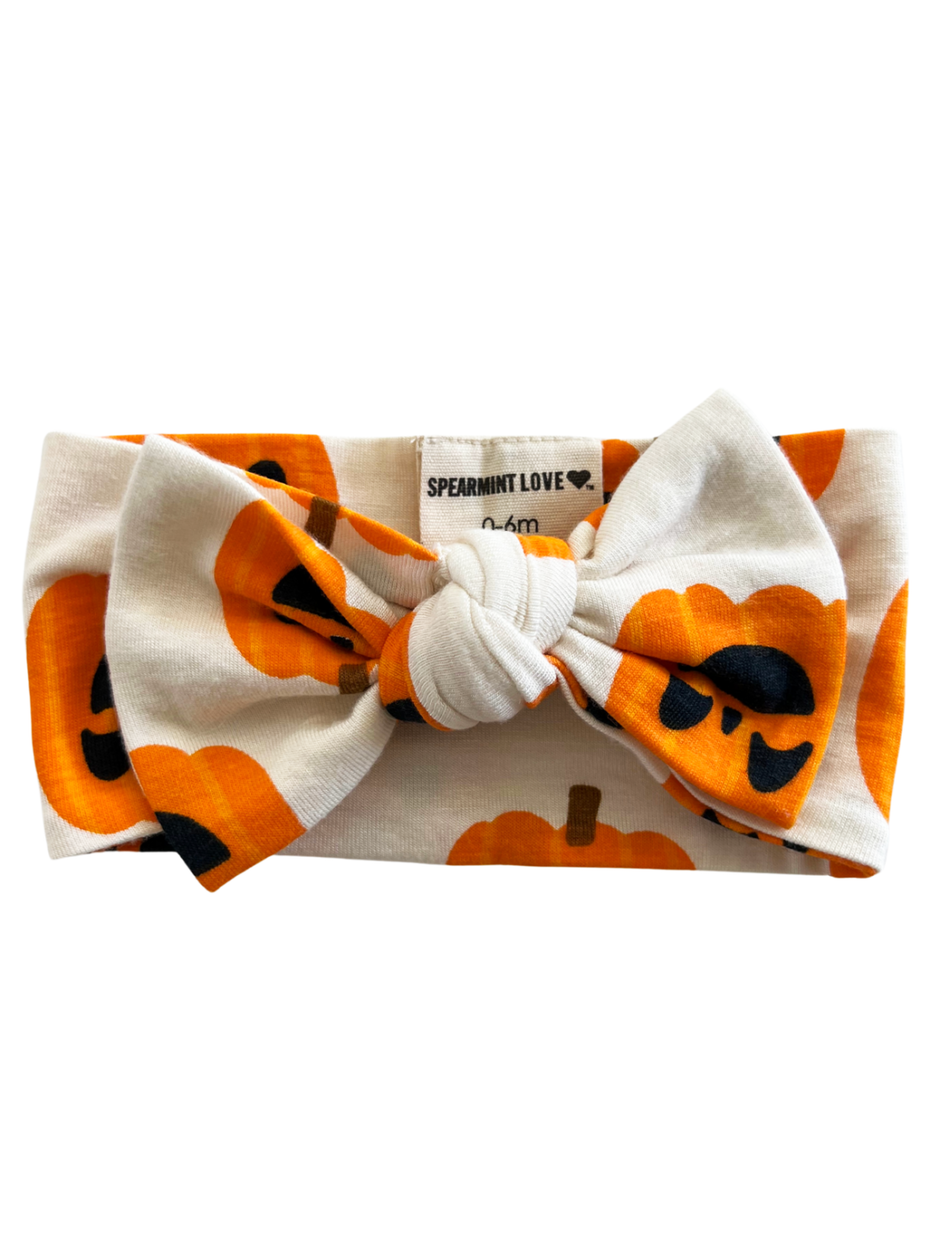 Pumpkin-patterned headband with a bow, designed for infants aged 0-6 months.