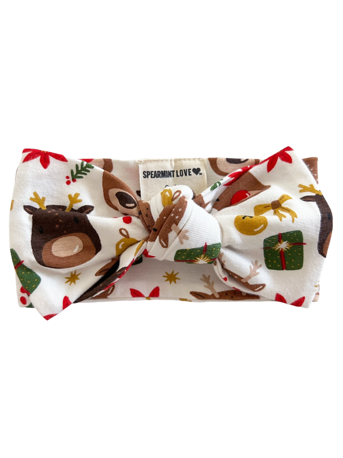 White bow headband with festive patterns of reindeer, gifts, and holiday elements. Brand label visible.