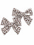 Pair of leopard print hair bows in white and brown, one with a clip and one without.