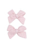 Two pastel pink fabric hair bows arranged neatly.