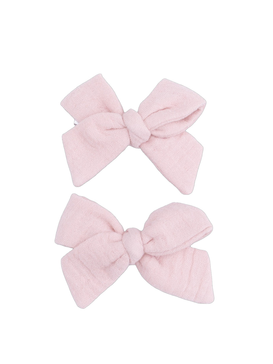 Two pastel pink fabric hair bows arranged neatly.