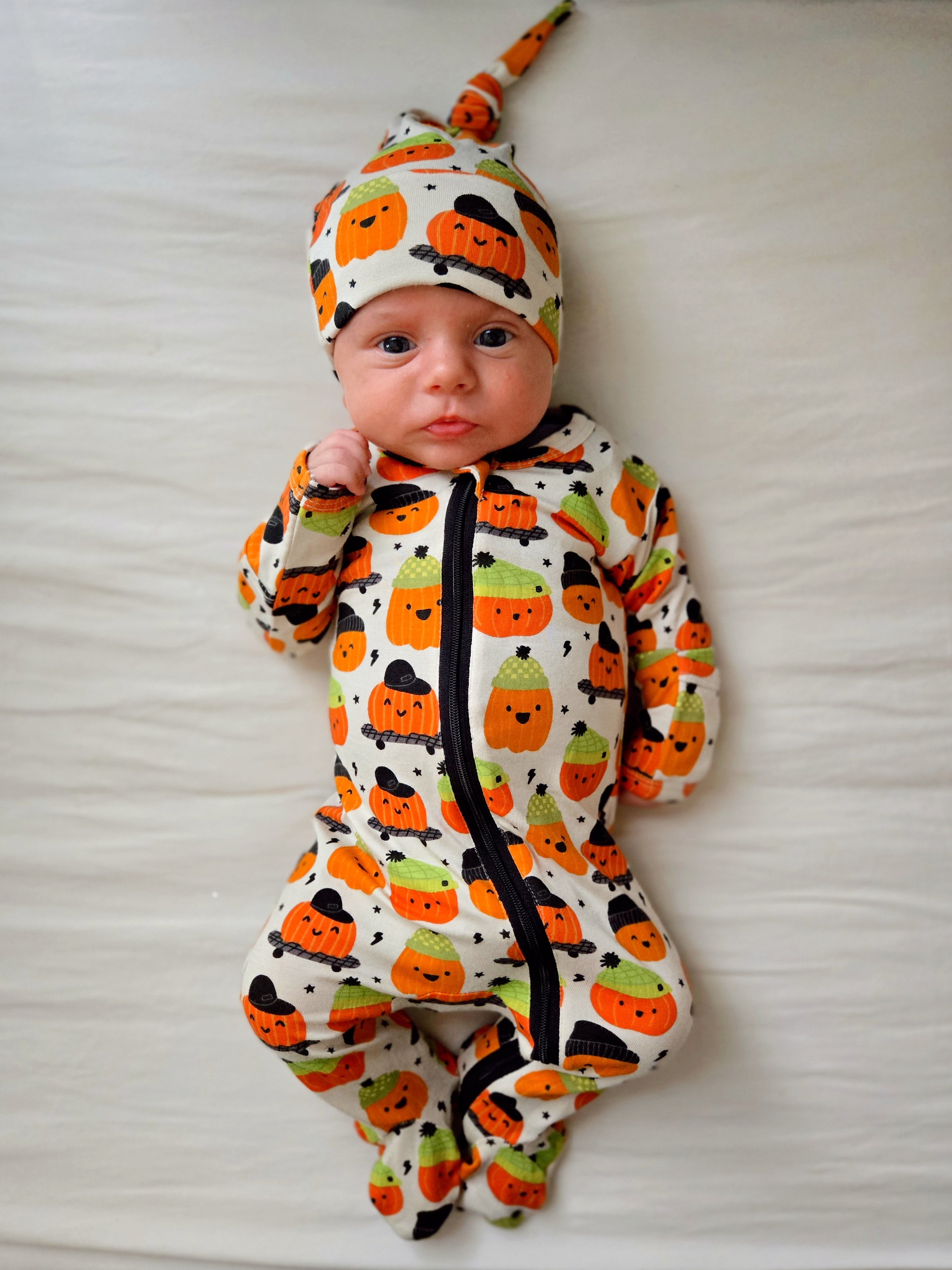 Baby wearing a Halloween-themed onesie and hat on a white background