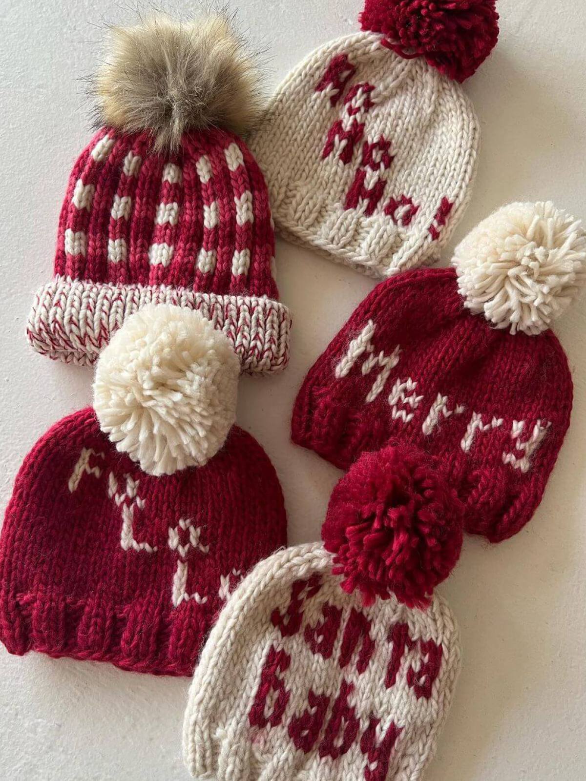 Collection of festive knitted winter hats in red and white with various playful phrases and pom-poms.
