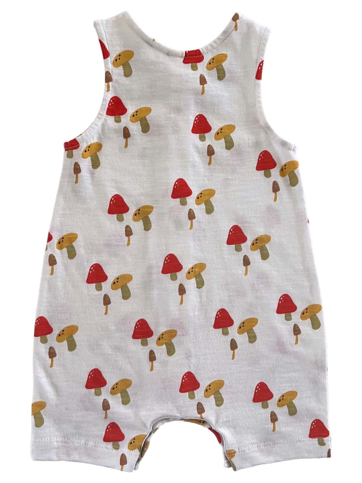 White romper with colorful mushroom print in red, yellow, and brown on the fabric.
