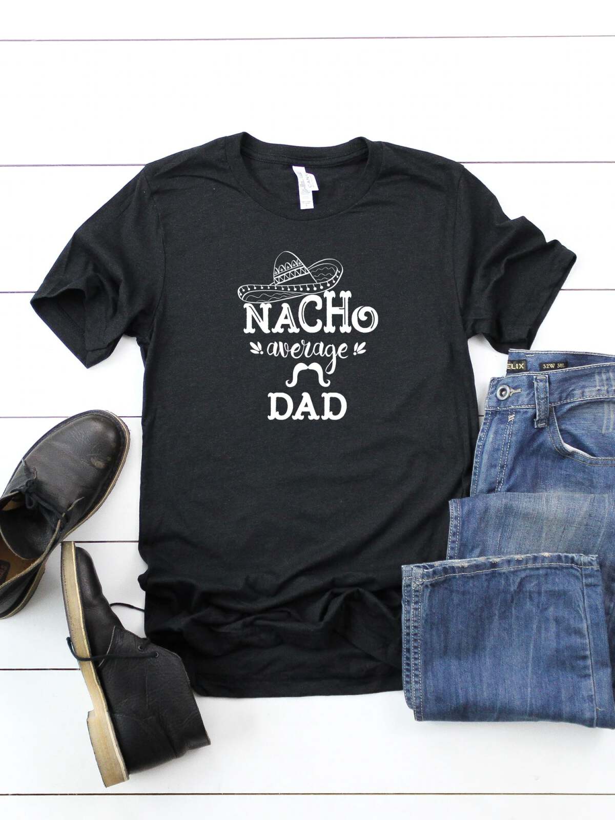 Black t-shirt with "Nacho Average Dad" text, styled with jeans and shoes on a white background.
