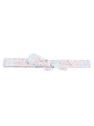 Pink patterned headband with a bow, featuring floral designs and zigzag edges.