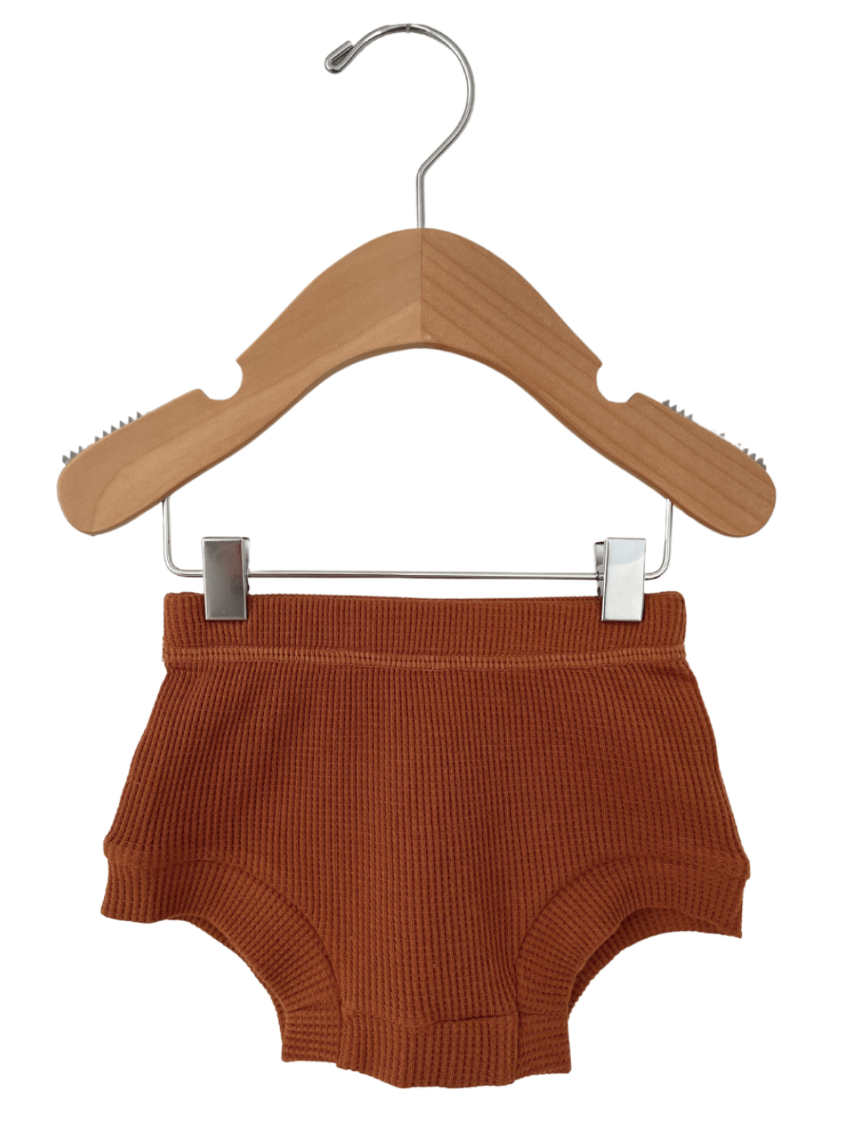Orange ribbed children's shorts hanging on a wooden hanger against a white background.