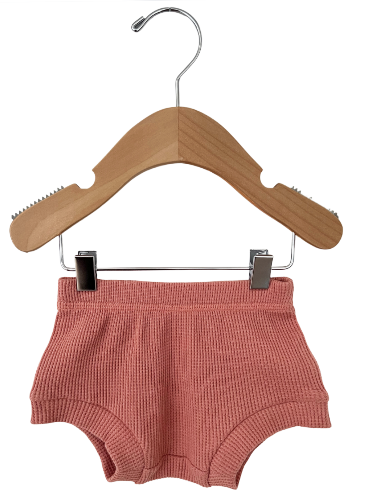 Pink ribbed kids' shorts on a wood hanger against a white background.