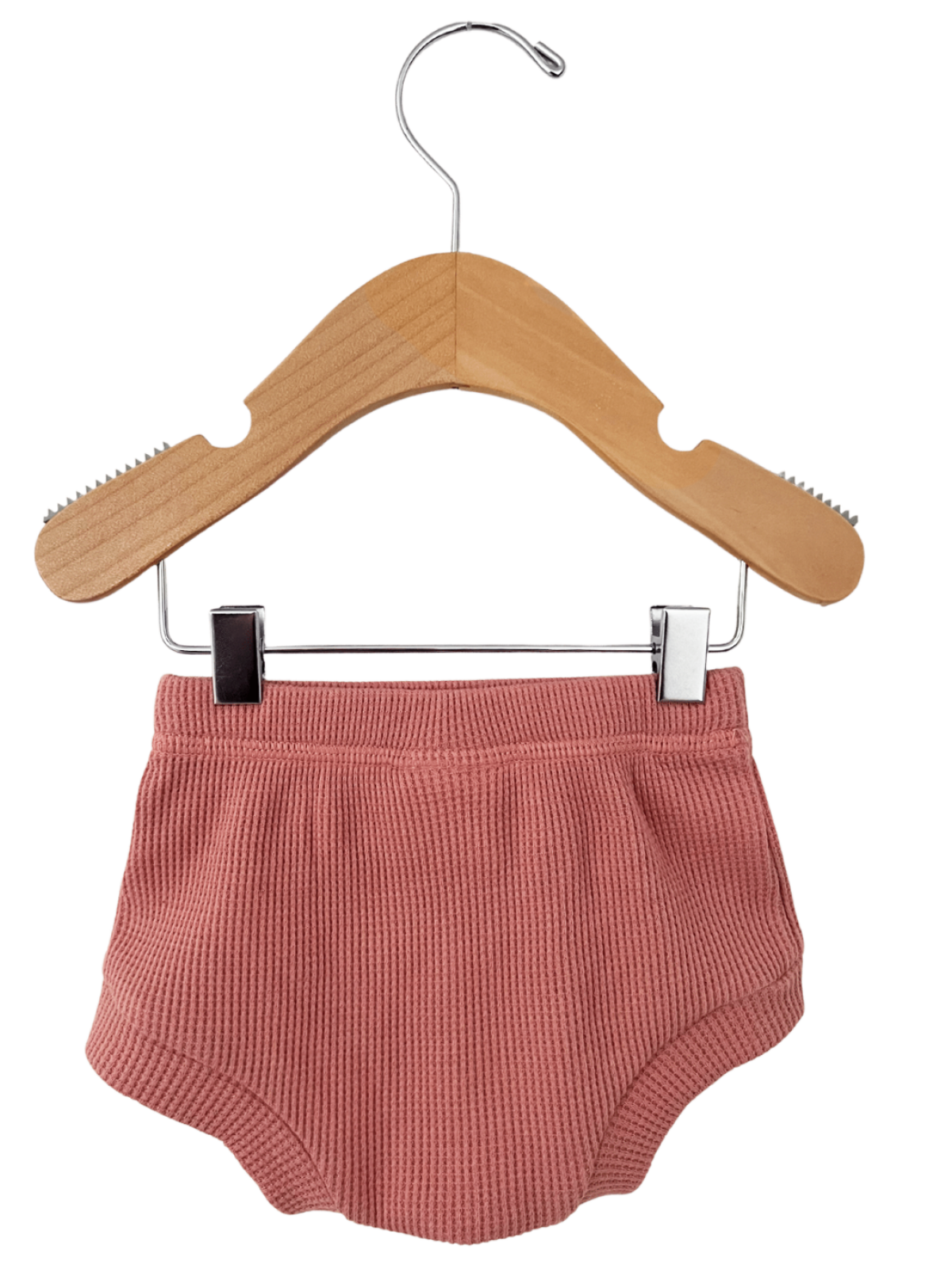 Light pink ribbed baby shorts hanging on a wooden clothes hanger.