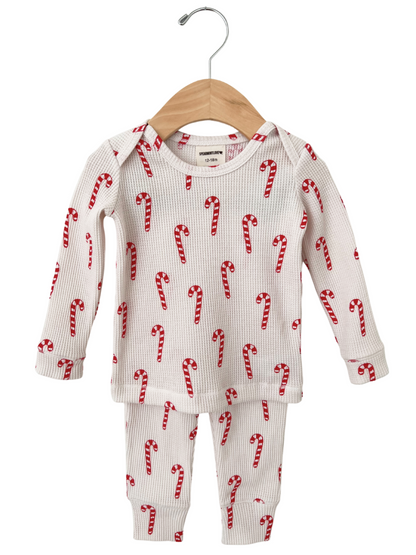 White children's pajama set with red candy cane print, hanging on a wooden hanger. Size 12-18 months.