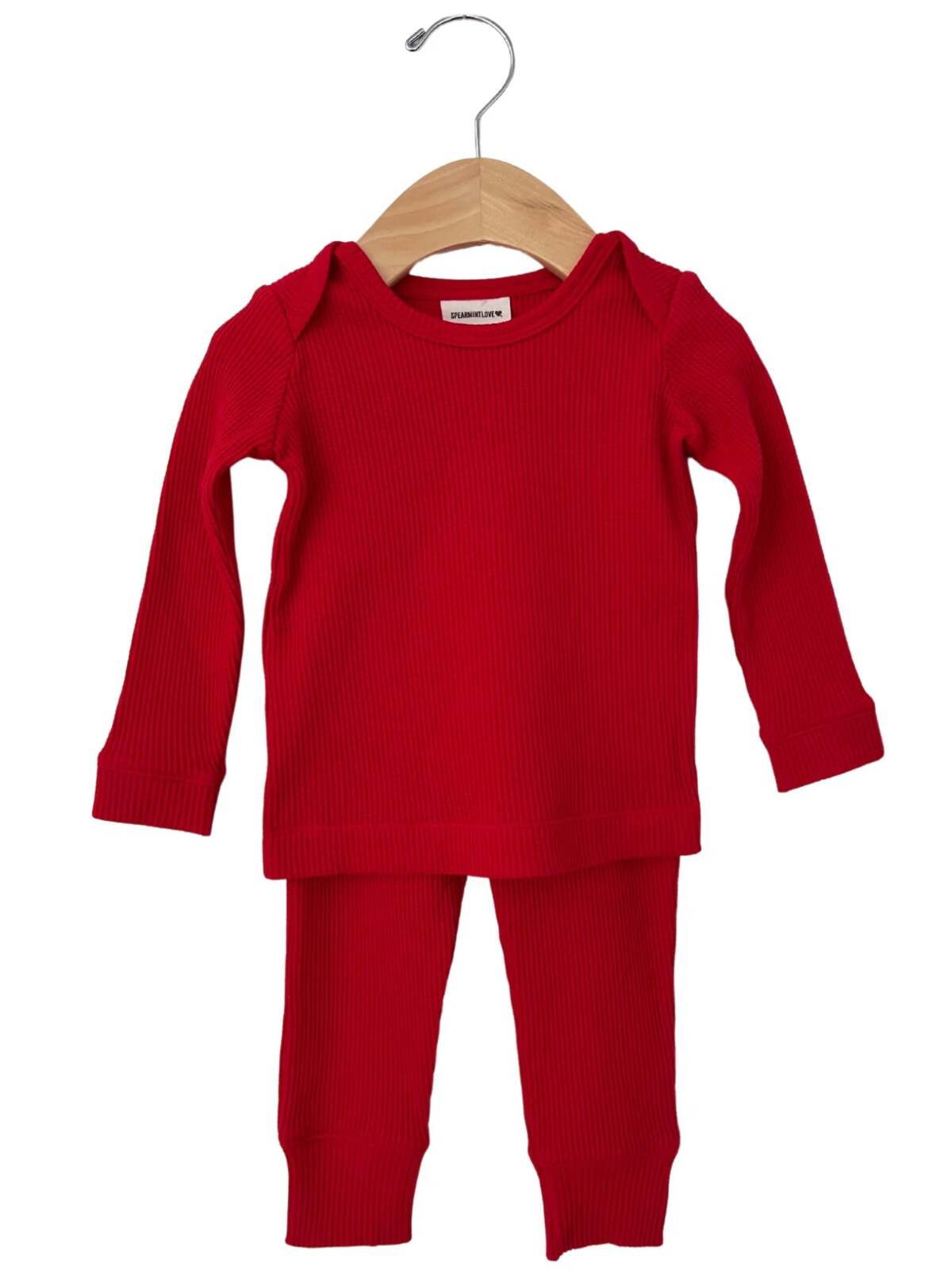 Red ribbed two-piece pajama set hanging on a wooden hanger.
