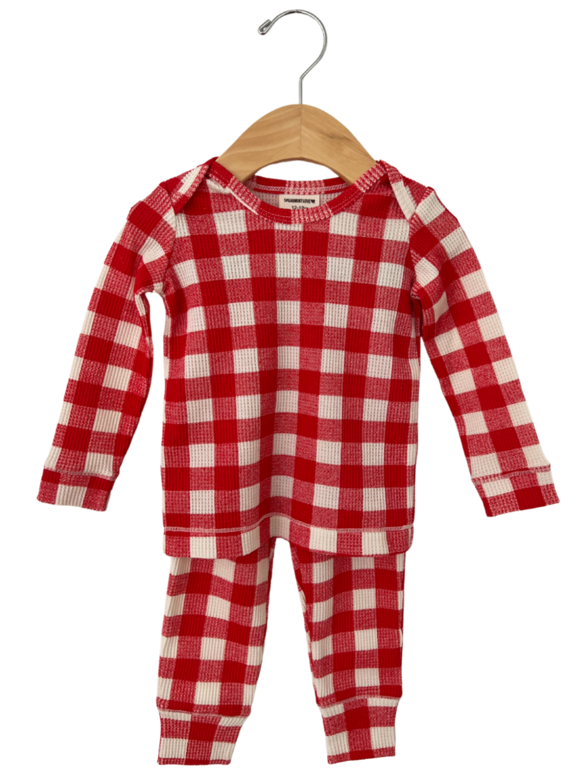 Red and white checkered infant pajamas hanging on a wooden hanger against a white background.