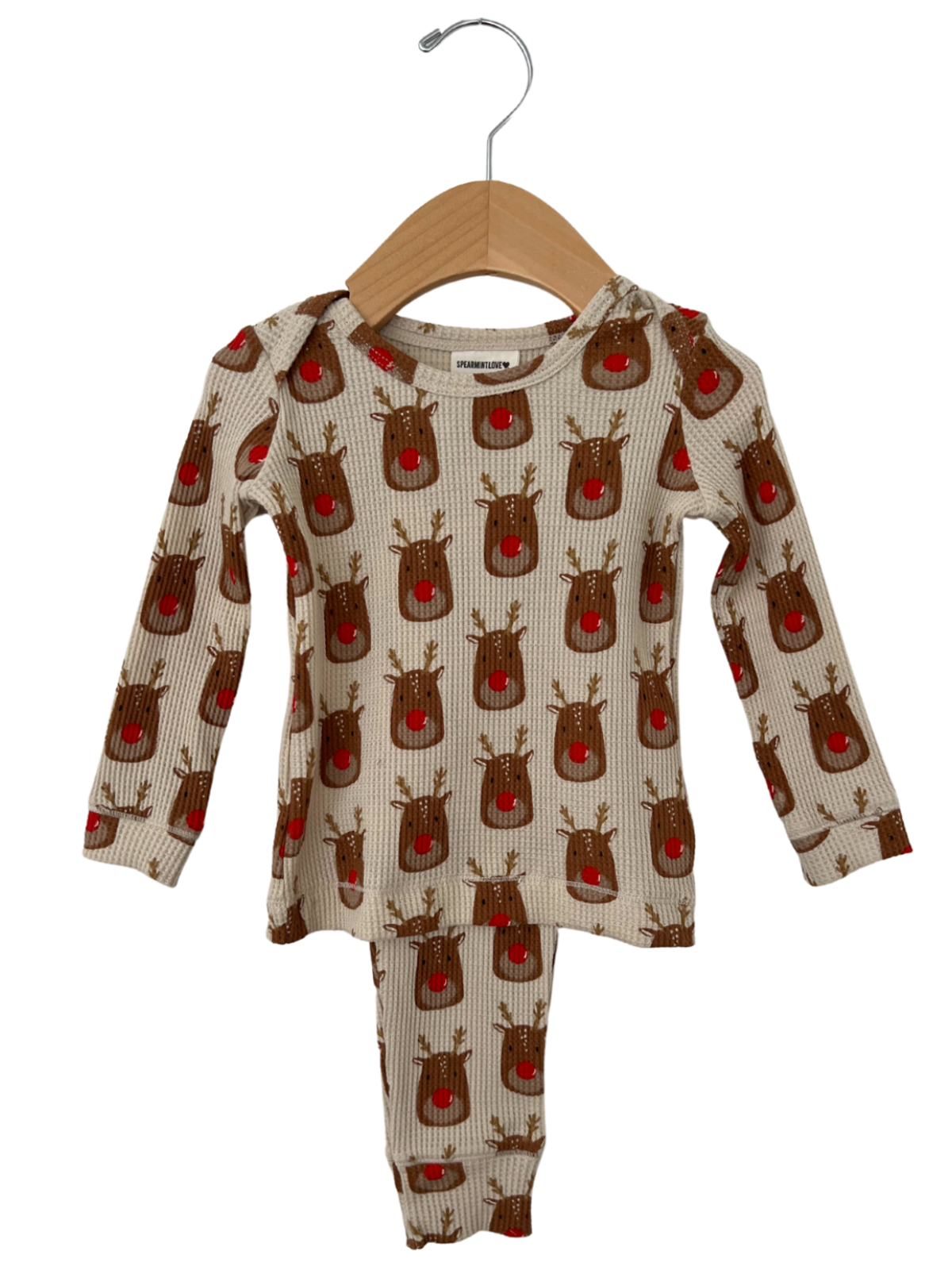 Reindeer-patterned children's pajama set on a wooden hanger, featuring long sleeves and pants.