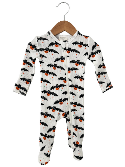 Baby onesie with bats and pumpkins design, hanging on a wooden hanger. Perfect for Halloween.