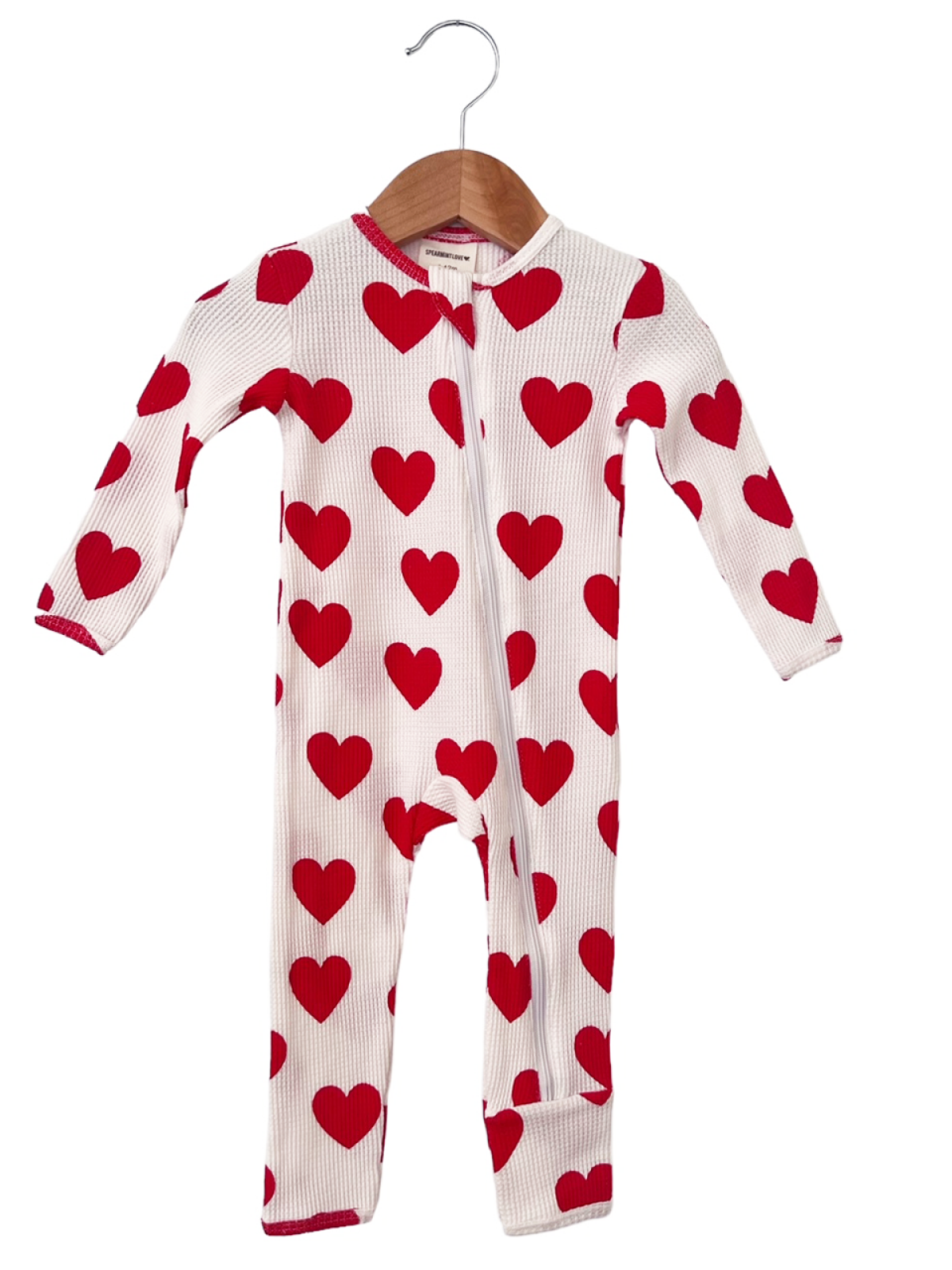 Red heart-patterned baby onesie hanging on a wooden hanger against a white background.