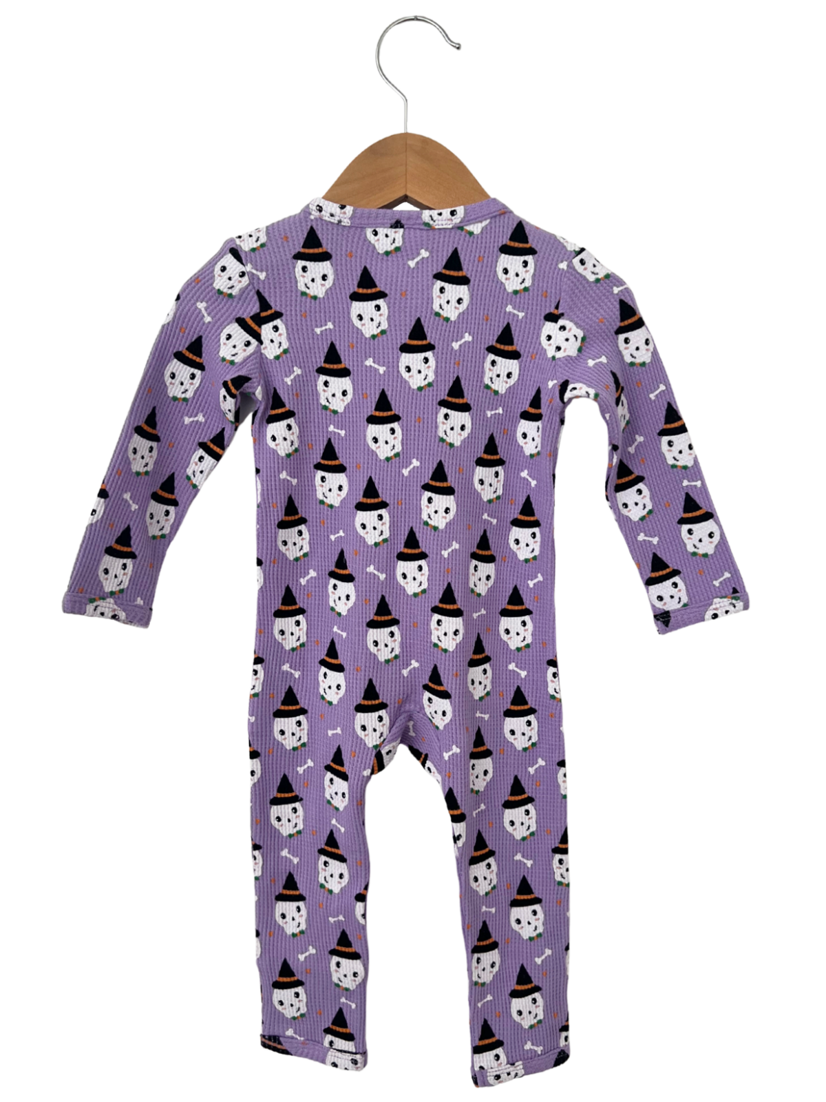 Purple baby onesie featuring playful ghost patterns and black hats, hanging on a wooden hanger.