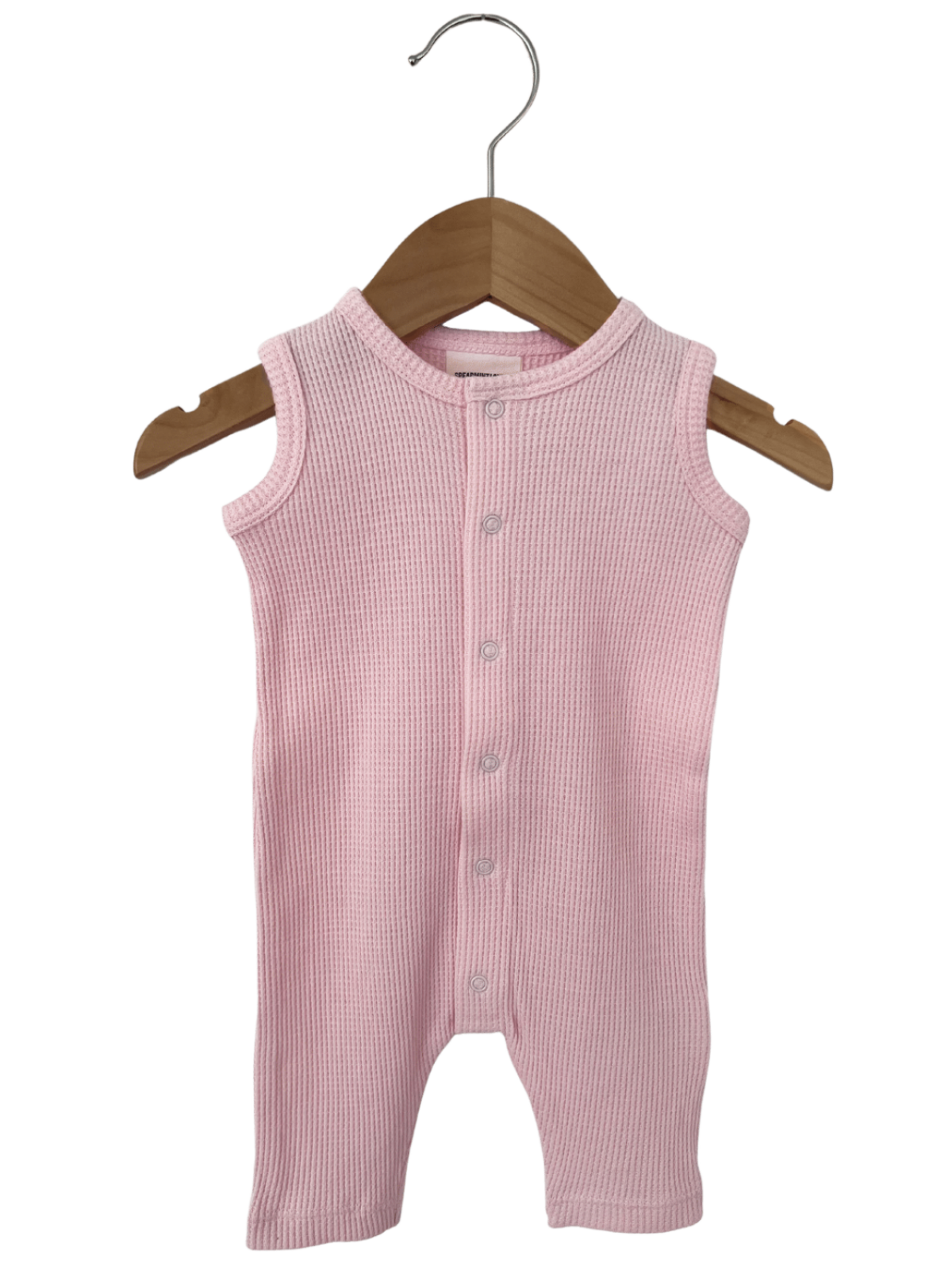 Light pink ribbed baby onesie hanging on a wooden hanger.