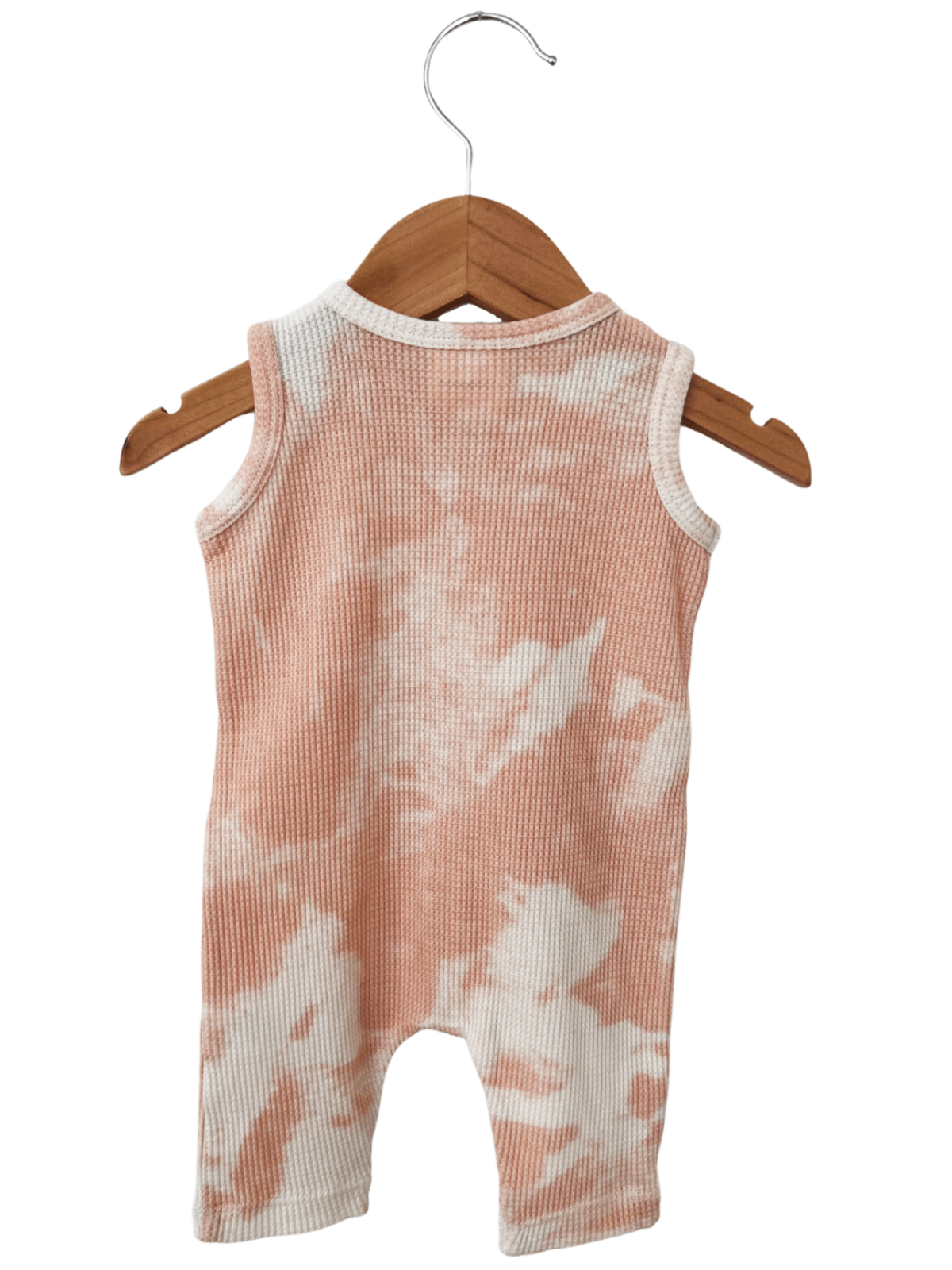 Peach and white tie-dye baby romper hanging on a wooden hanger.