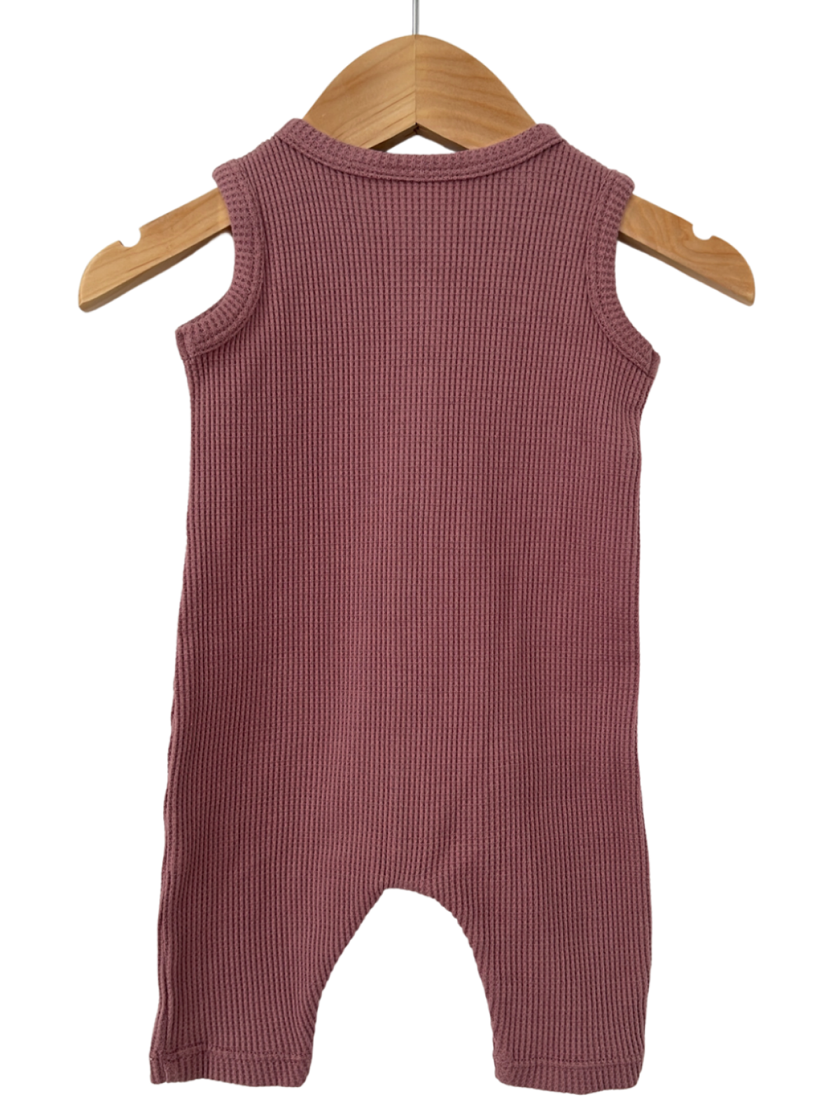 Back view of a ribbed, sleeveless infant romper in soft mauve, hanging on a wooden hanger.