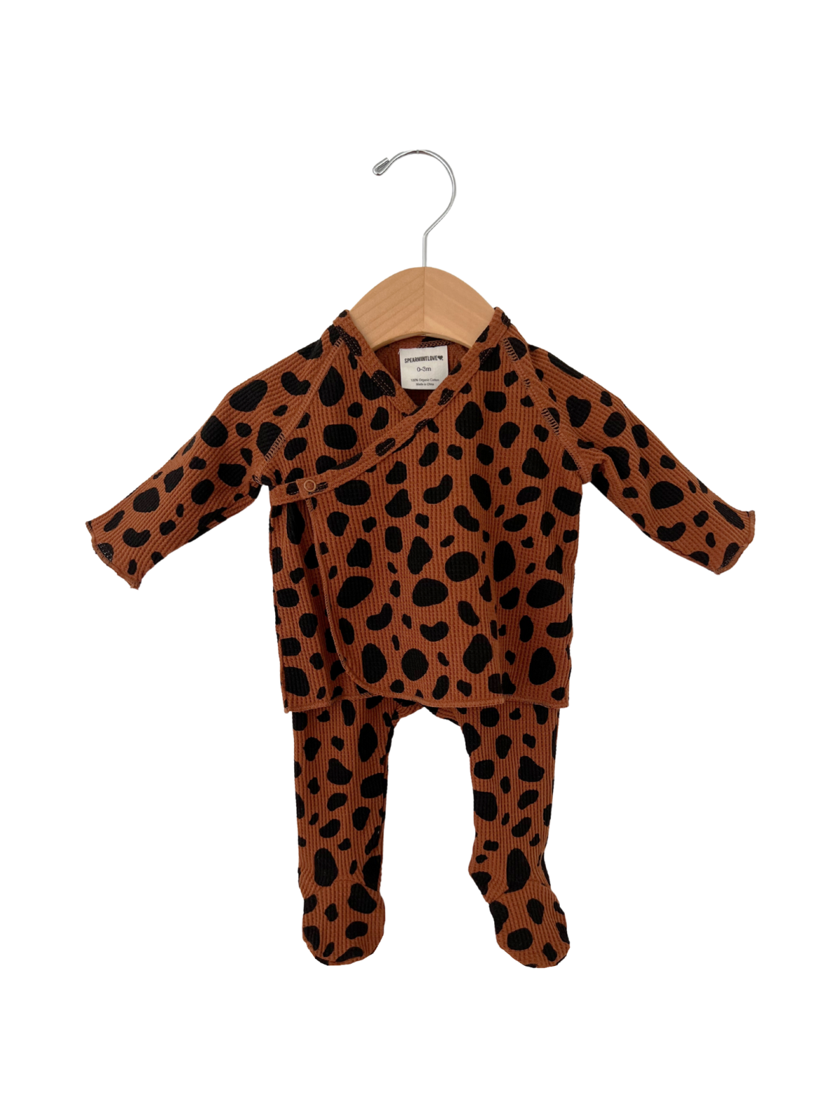 Brown baby outfit with black polka dots, featuring a long-sleeve top and matching pants on a wooden hanger.