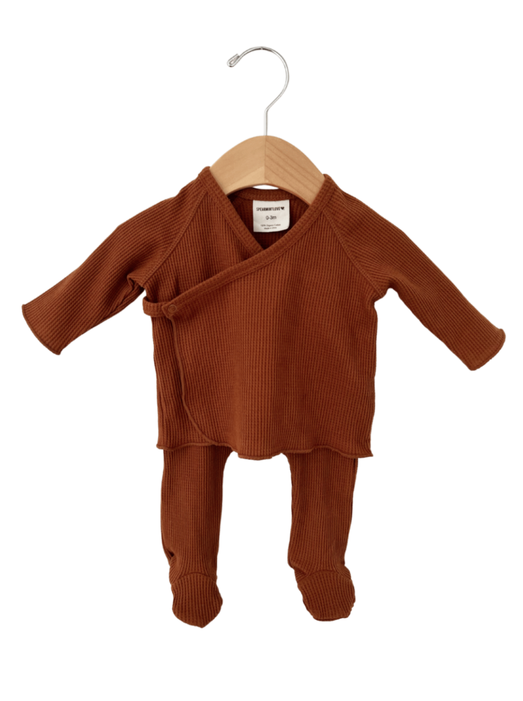 Rust-colored baby outfit hanging on a wooden hanger, featuring long sleeves and matching pants.