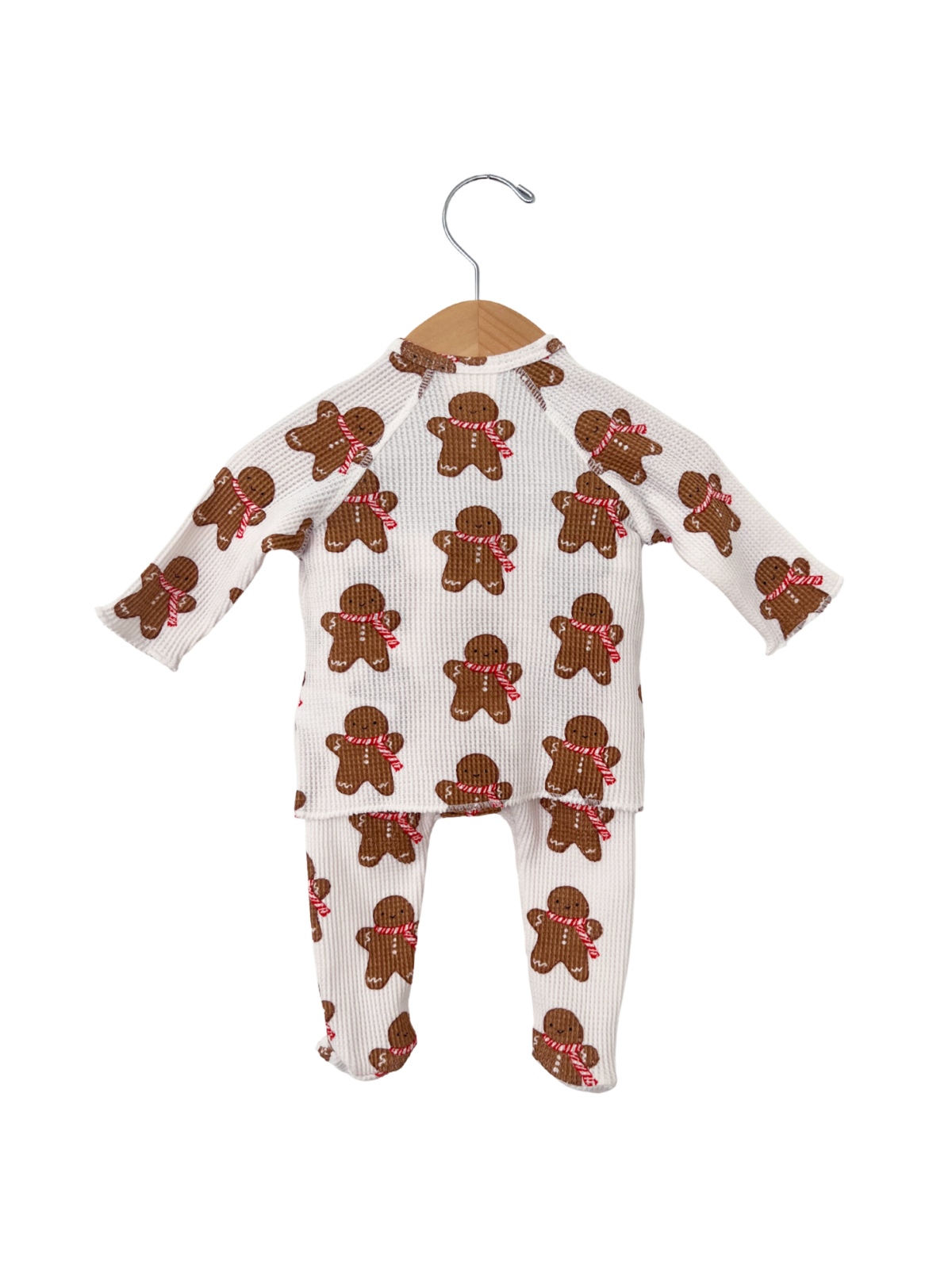 Gingerbread-themed children's pajama set hanging on a wooden hanger.