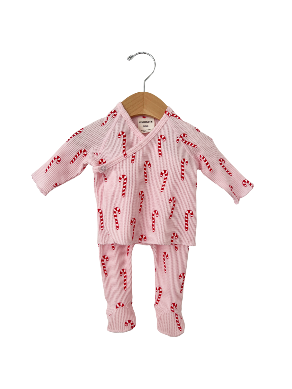 Pink baby outfit with candy cane pattern, featuring a wrap top and matching pants, displayed on a wooden hanger.