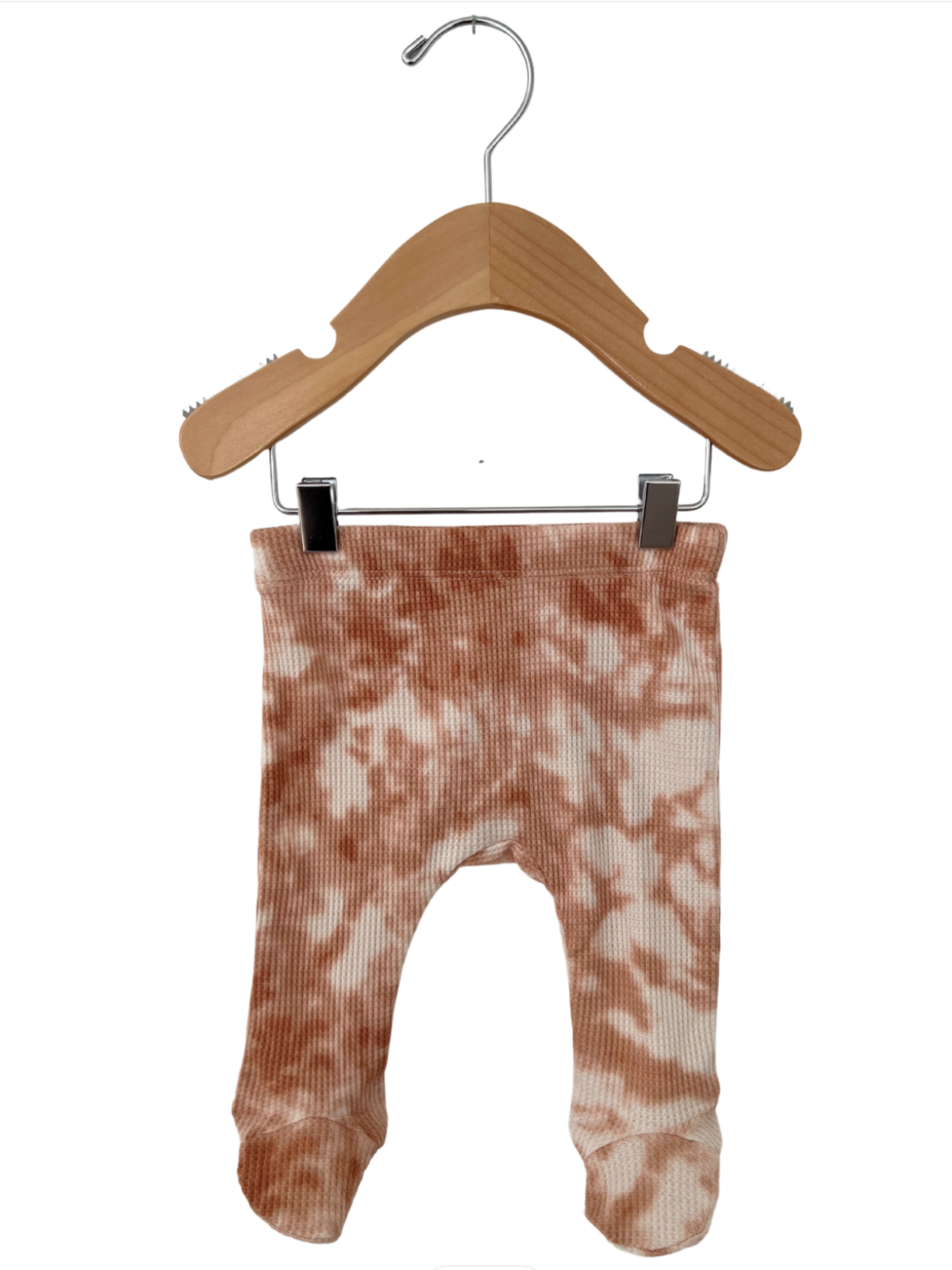 Soft ribbed infant leggings in a peach tie-dye pattern, displayed on a wooden hanger.