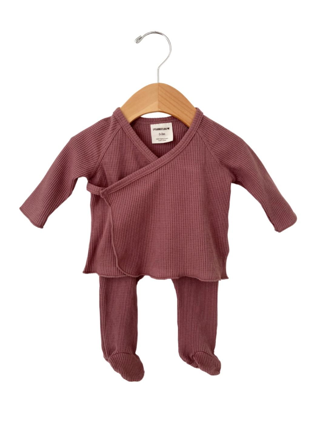 Pink ribbed baby outfit on a wooden hanger, featuring long sleeves and footed pants. Suitable for newborns.