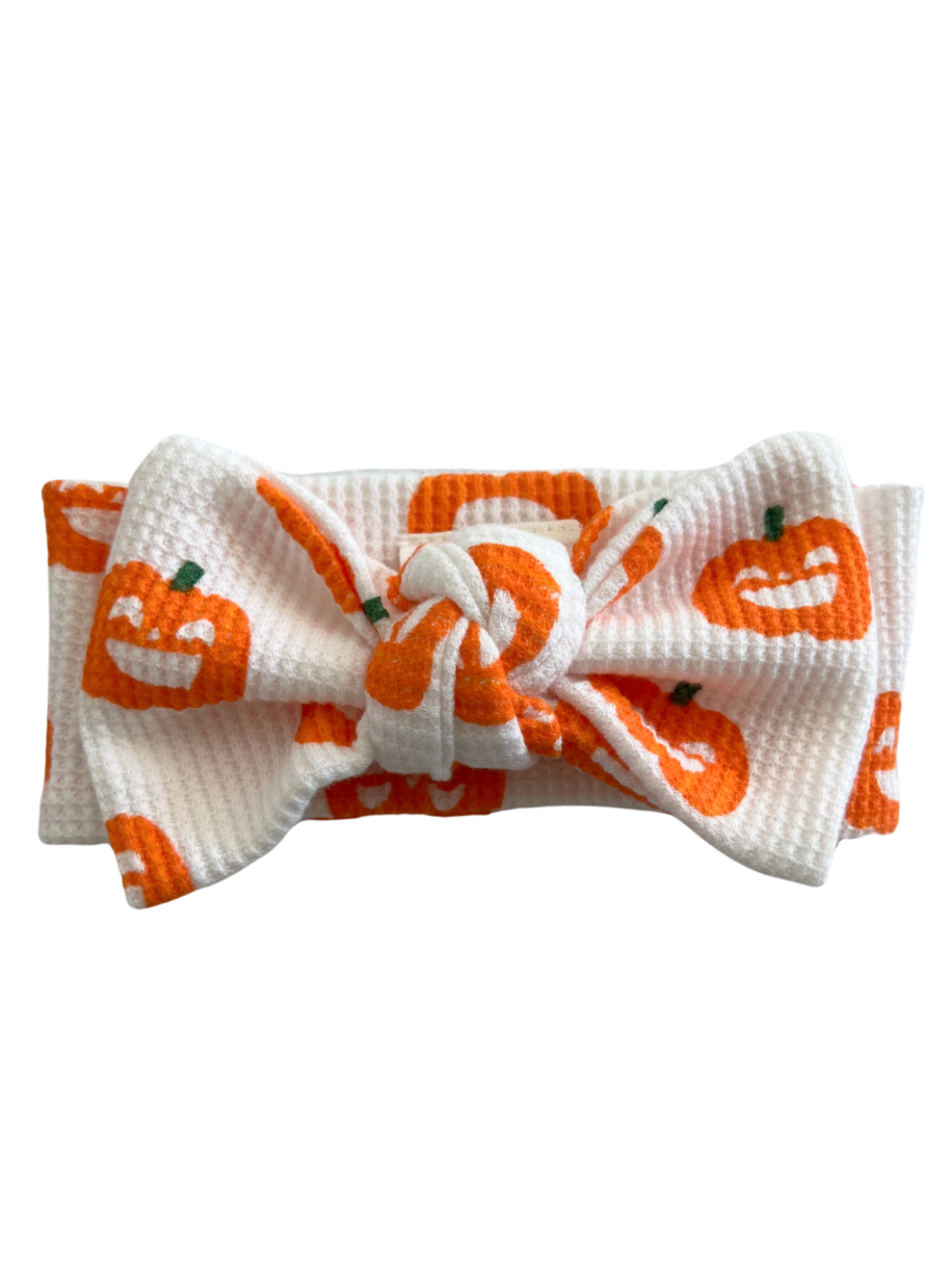 White headband with an orange pumpkin pattern and a knotted bow at the center.