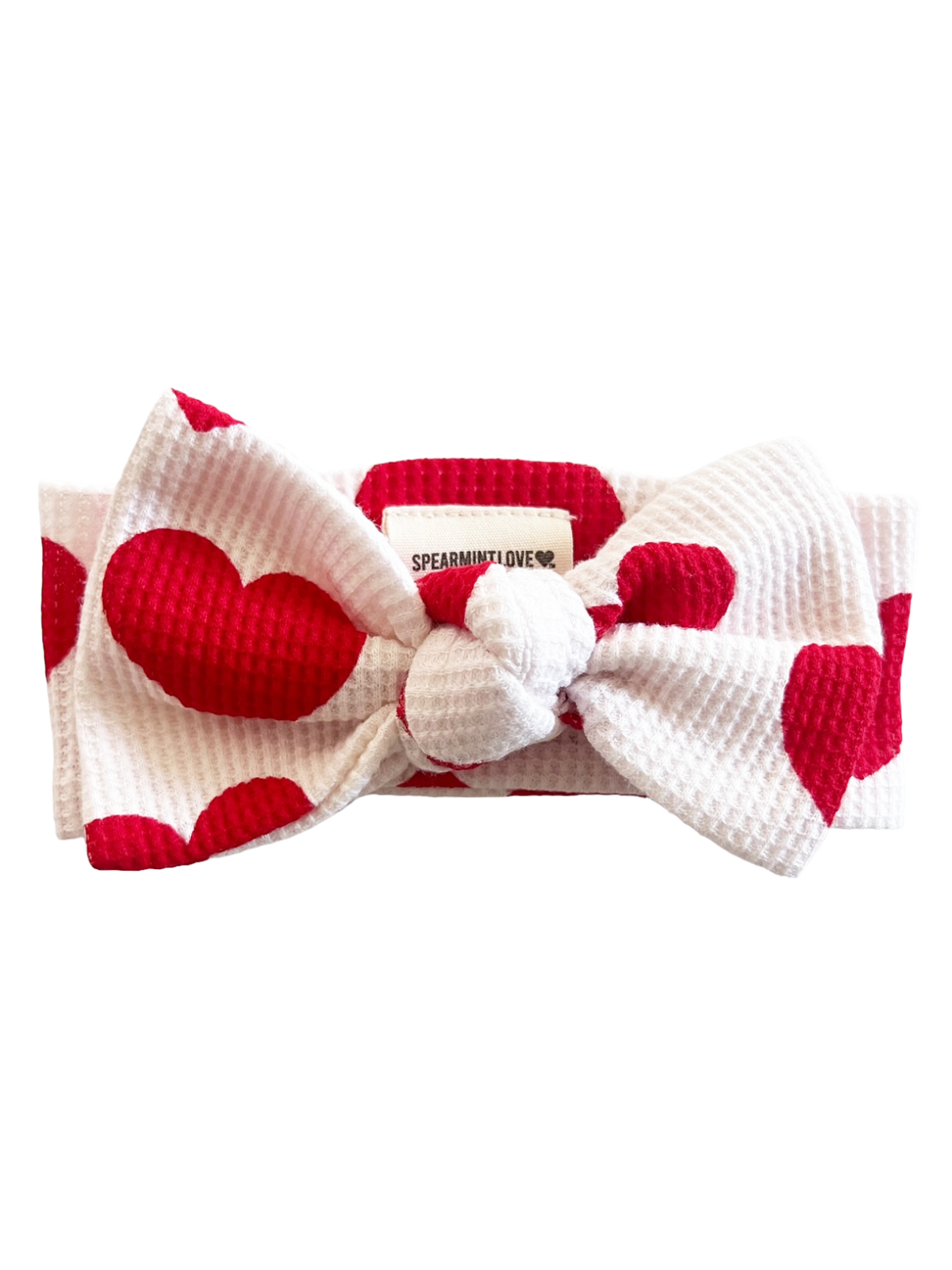 White headband with large red hearts and a center knot, featuring a tag that says "SPEARMINT LOVE."